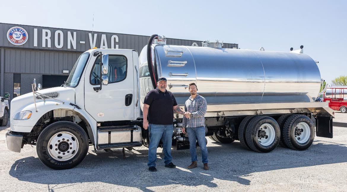 The owner of Dump N Pump Septic standing by the service truck